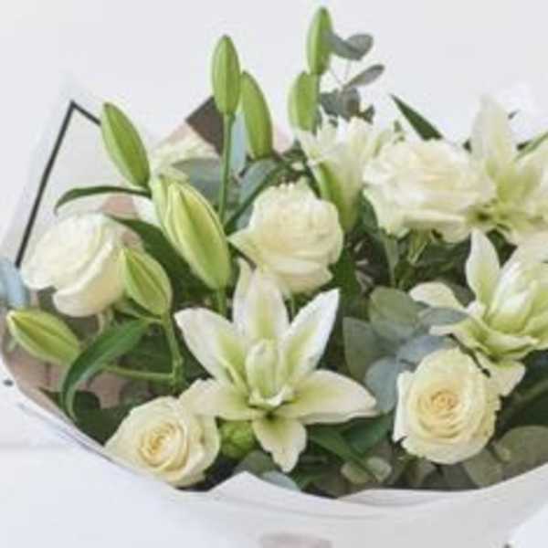 Bouquet of white lilies and roses wrapped in paper