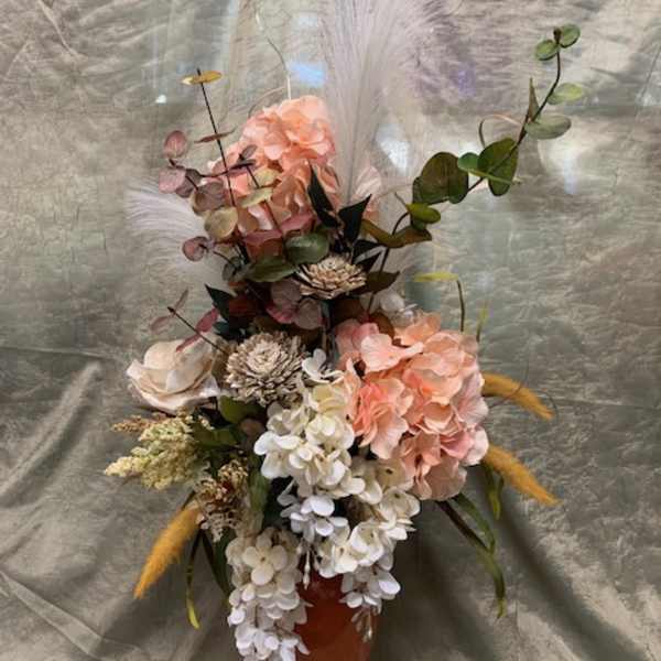 Tall floral arrangement in an orange vase with pink and white blooms