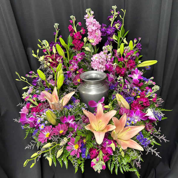 Colorful floral wreath around a silver urn on black drape