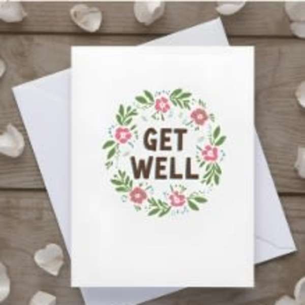 White get well greeting card with floral wreath design and matching white envelope underneath.