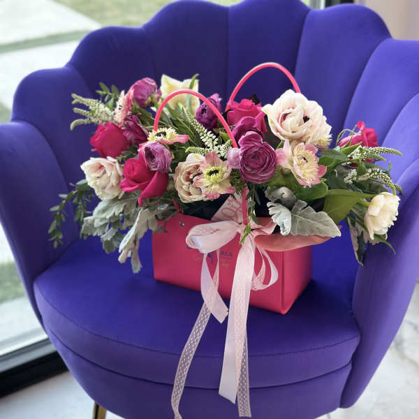 Pink and white flower arrangement in a gift bag with ribbon