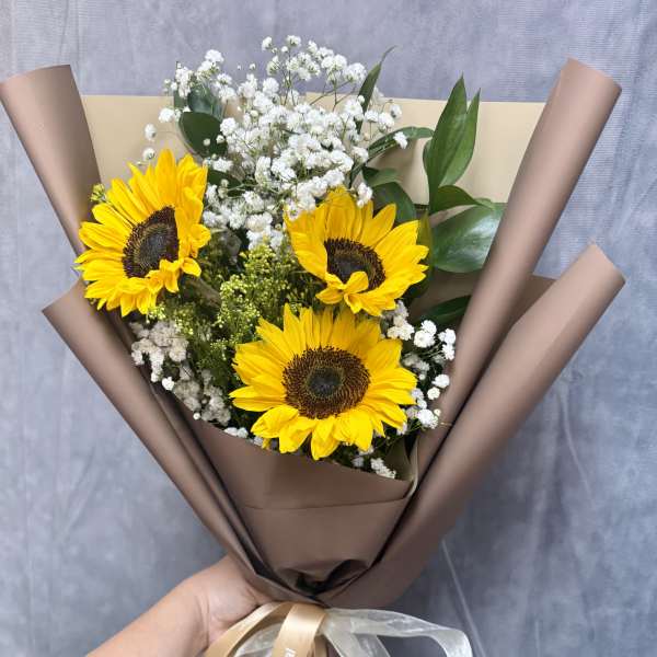 Bouquet of sunflowers and white baby's breath wrapped in brown paper
