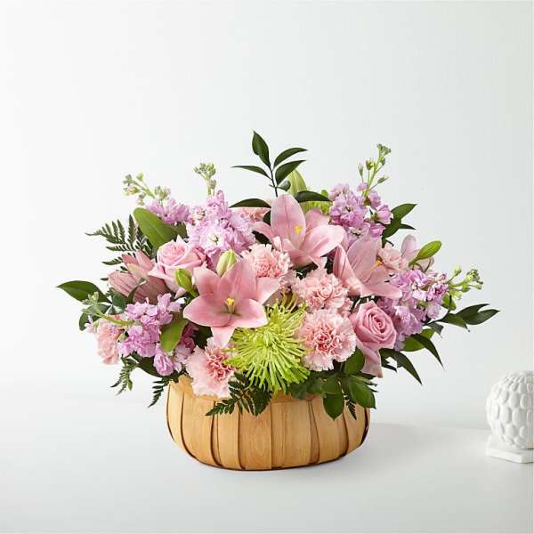 Pink floral arrangement in a woven basket with lilies and roses