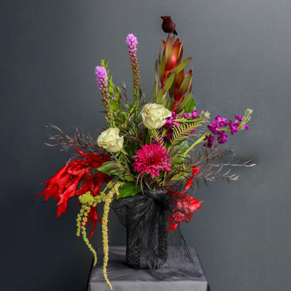 Tall floral arrangement with pink, white, and red blooms in a black vase