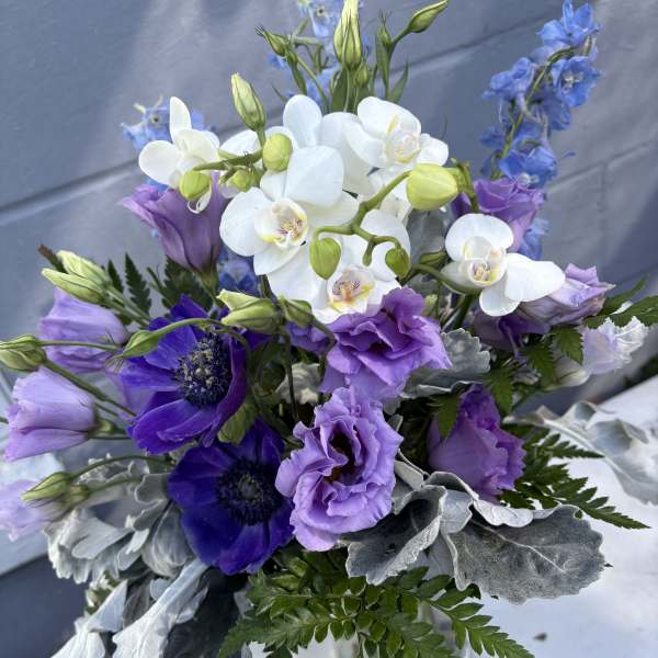 Bouquet of white orchids and purple flowers with silver foliage