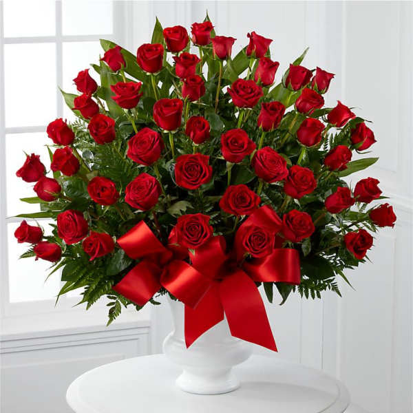 Large bouquet of red roses in a white vase with a red ribbon