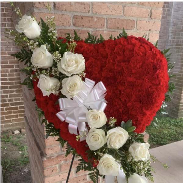 Heart-shaped red floral arrangement with white roses and a white bow