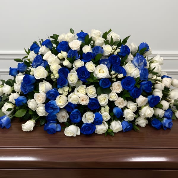 Large arrangement of blue and white roses on a wooden casket