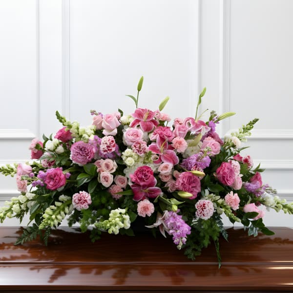 Large pink and white floral casket spray on a polished coffin
