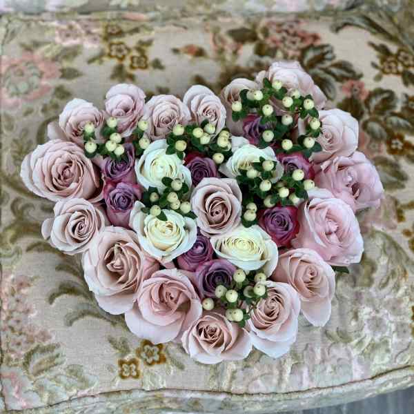 Heart-shaped bouquet of pale pink and white roses with small berry sprigs