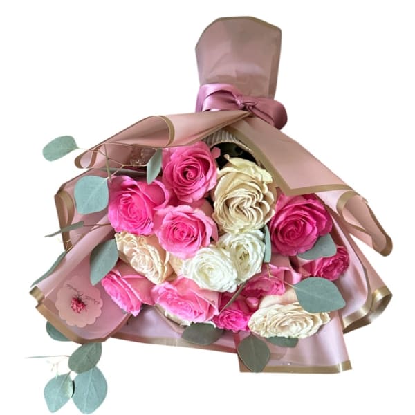 Bouquet of pink and cream roses wrapped in blush paper with ribbon