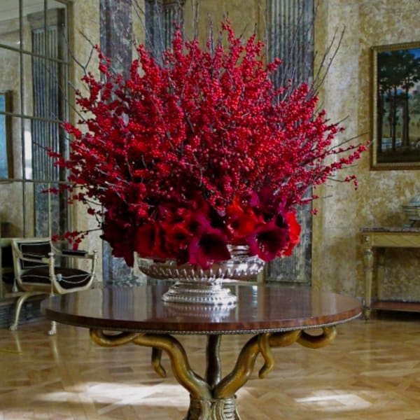 Large red floral centerpiece in a silver urn on a round table