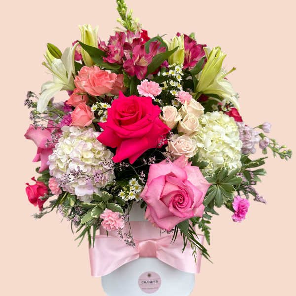 Pink and white mixed flower arrangement in a round box with a satin ribbon