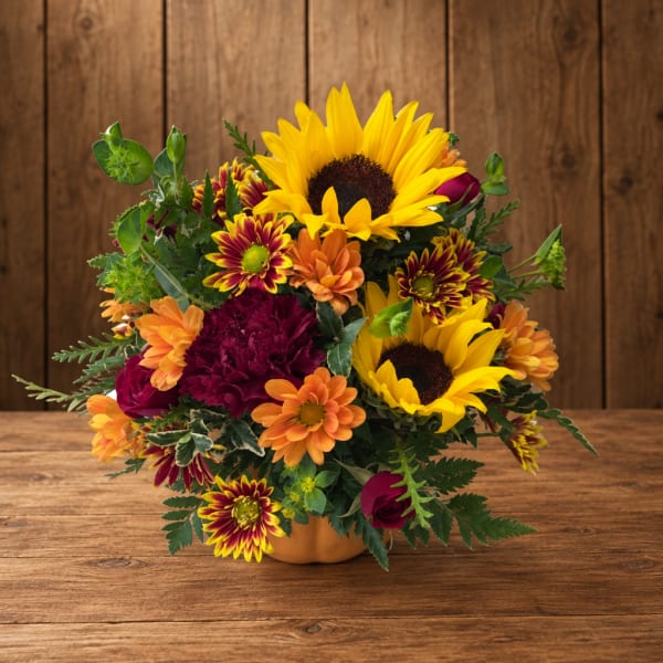 Mixed bouquet with sunflowers, chrysanthemums, and roses in a low vase