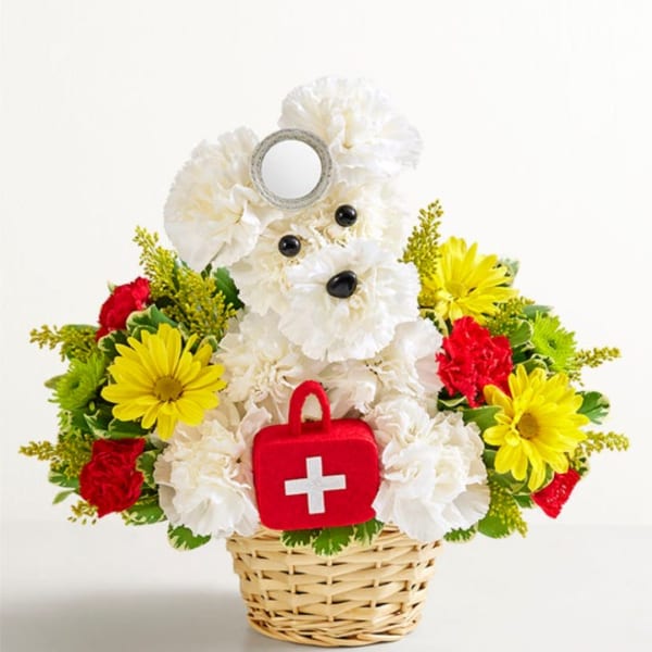 White teddy bear floral arrangement in a basket with a red first-aid bag