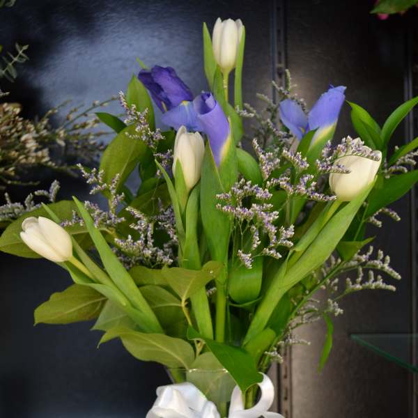 Bouquet of purple and white tulips in a glass vase with a white ribbon