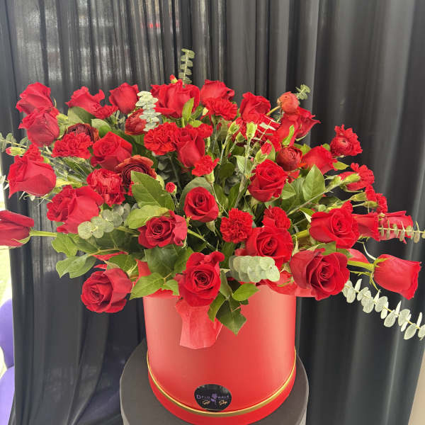Red roses and carnations arranged in a red hat box