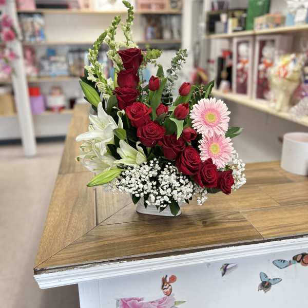 Red roses, white lilies, and pink daisies in a white vase