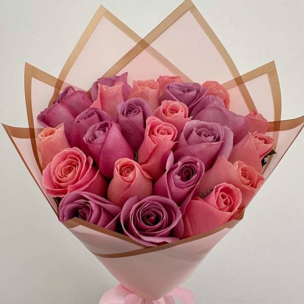 Bouquet of pink and purple roses wrapped in pink paper with a ribbon