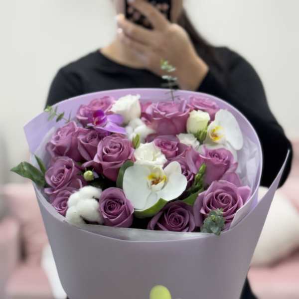 Bouquet of purple roses and white orchids wrapped in lavender paper