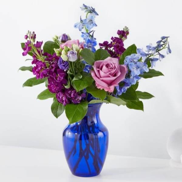 Pink rose bouquet with blue and purple flowers in a cobalt vase