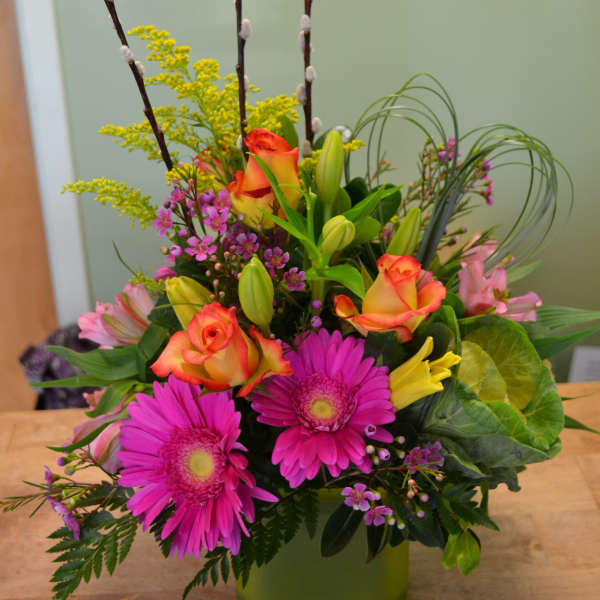 Mixed bouquet in a green vase with pink daisies, roses, and lilies