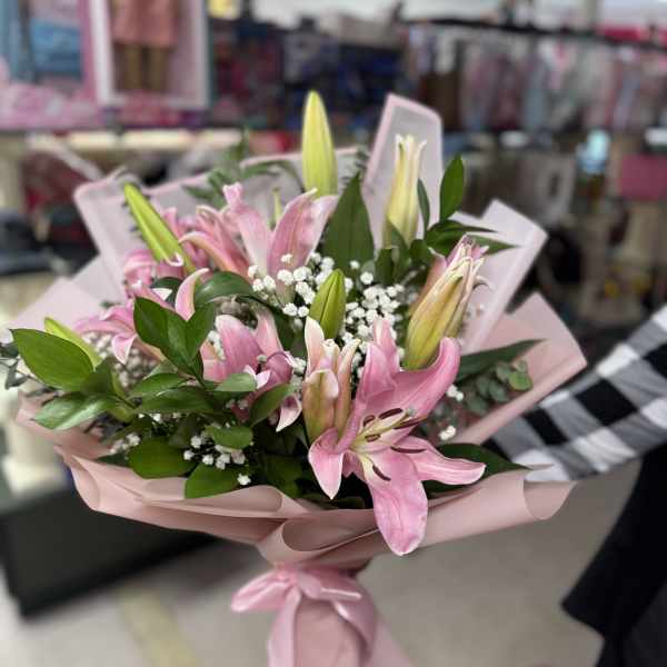 Pink lily bouquet wrapped in blush paper with a ribbon