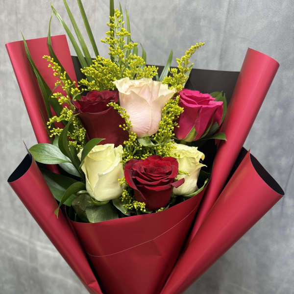 Bouquet of red, white, and pink roses wrapped in burgundy paper