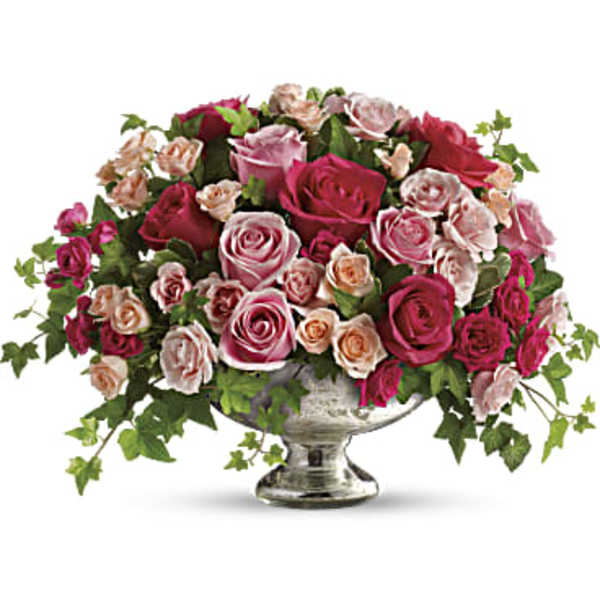 Pink and peach roses arranged in a silver pedestal vase