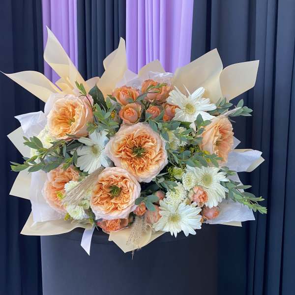Peach roses and white daisies in a wrapped bouquet