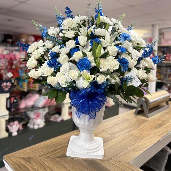White and blue floral arrangement in a white urn vase