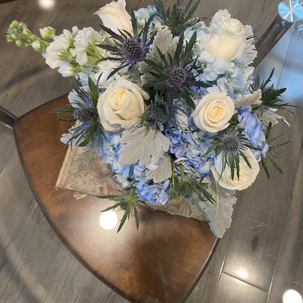 Bouquet of white roses and blue hydrangeas with spiky thistle flowers