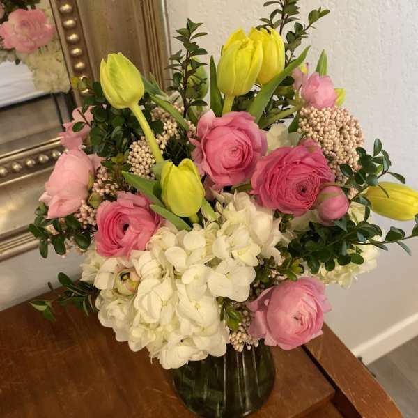 Pink and white bouquet with yellow tulips in a glass vase