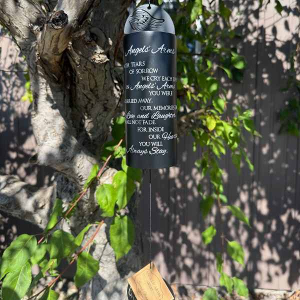 Black memorial wind chime hanging from a tree branch
