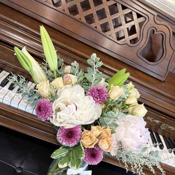 Bouquet of lilies, roses, and purple mums in a glass vase