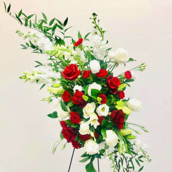 Tall standing arrangement of red and white roses with white lilies and greenery