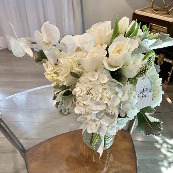 White floral bouquet in a glass vase with a Mother's Day tag