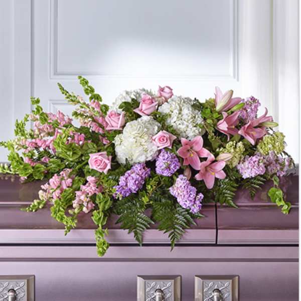 Pastel pink and white casket spray with roses, lilies, and hydrangeas on a lavender casket.