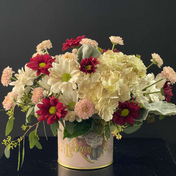 Mixed bouquet of white and red flowers in a decorative tin container