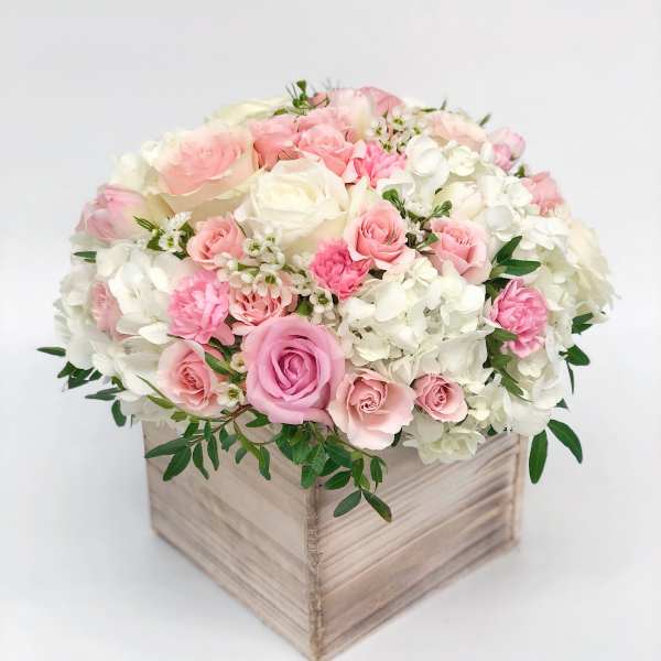 Pink and white roses arranged in a wooden box