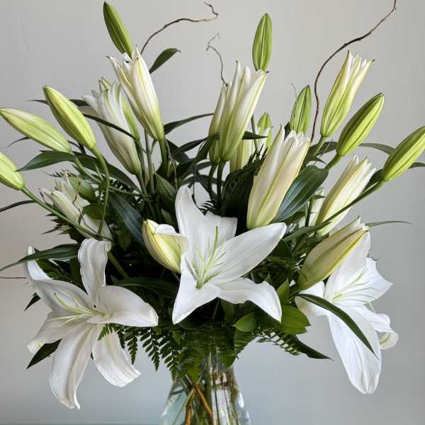 White lilies arranged in a clear glass vase