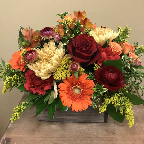 Mixed bouquet with red roses, orange gerberas, and cream chrysanthemums in a wooden box