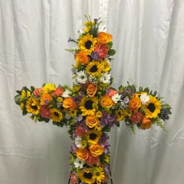 Cross-shaped floral tribute with sunflowers, orange roses, and mixed blooms
