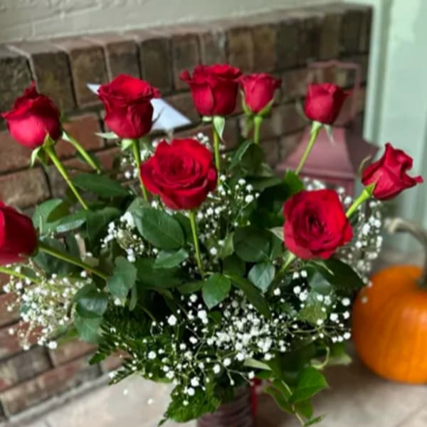 Red roses arranged in a vase with baby's breath