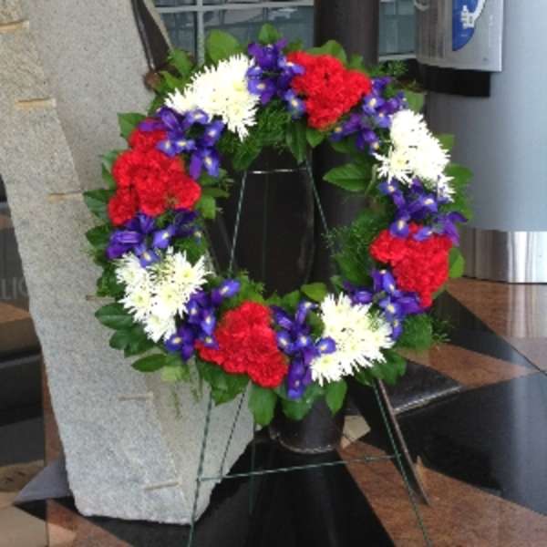 Patriotic standing wreath with red, white, and purple flowers on a metal easel