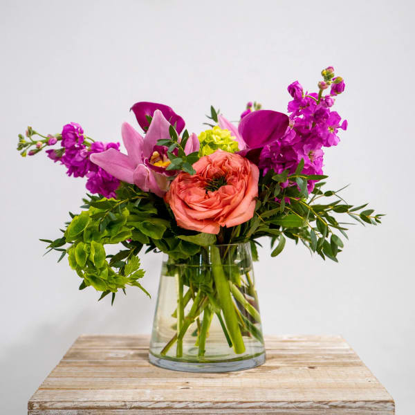Pink and purple flowers arranged in a clear glass vase