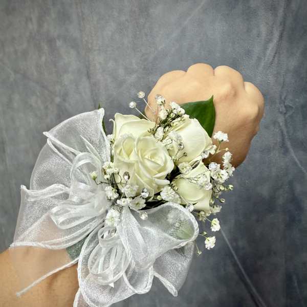 White rose wrist corsage with baby's breath and a sheer ribbon bow