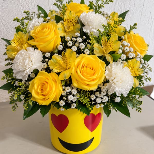 Yellow roses and white carnations in a smiley-face container
