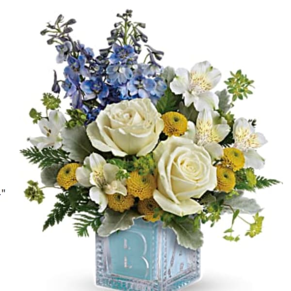 White roses and blue flowers in a blue cube vase
