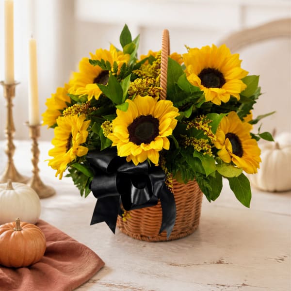 Basket of yellow sunflowers with a black ribbon on a table